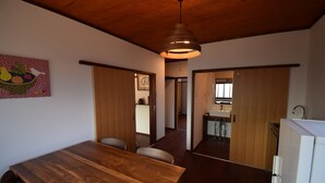 A modern kitchen with wooden cabinets, a white refrigerator, and a wooden dining table with chairs. - Quaint House Naoshima (Naoshima)