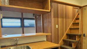 A modern kitchen with a wooden countertop, stainless steel sink, and built-in wooden shelving. - Quaint House Naoshima (Naoshima)