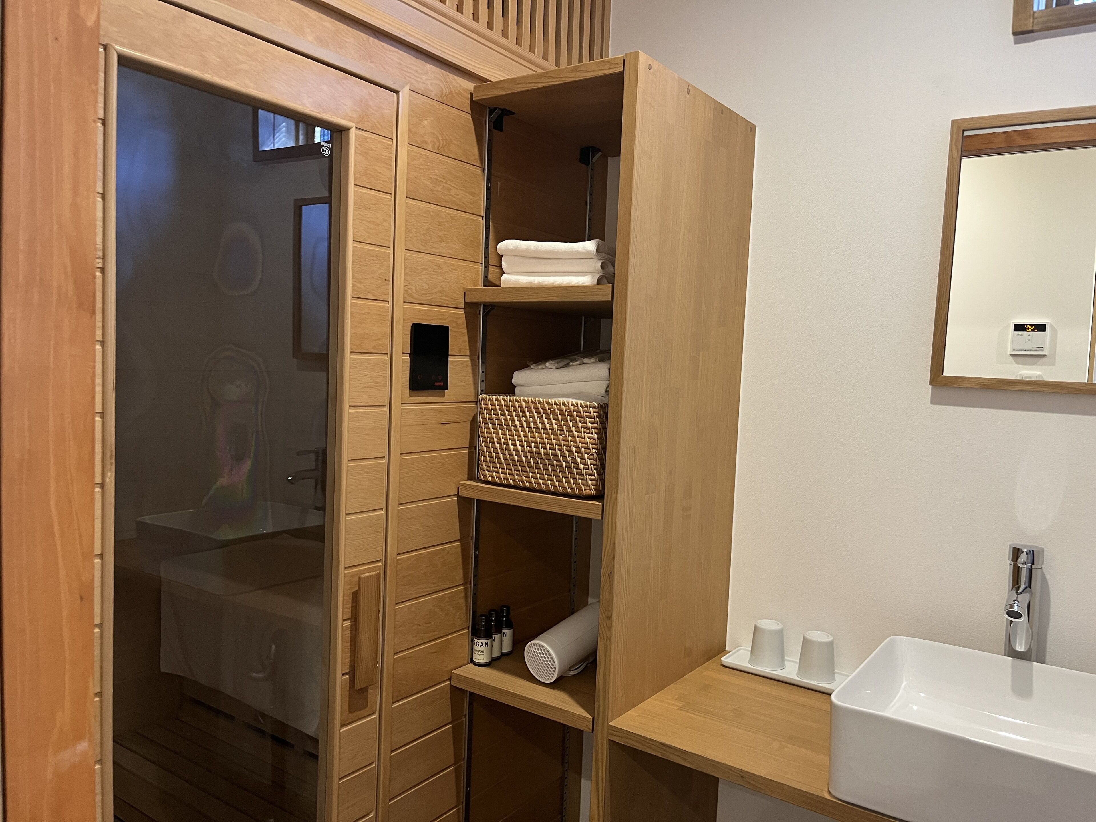 A modern bathroom with a wooden vanity, a large mirror, and a built-in shower area.