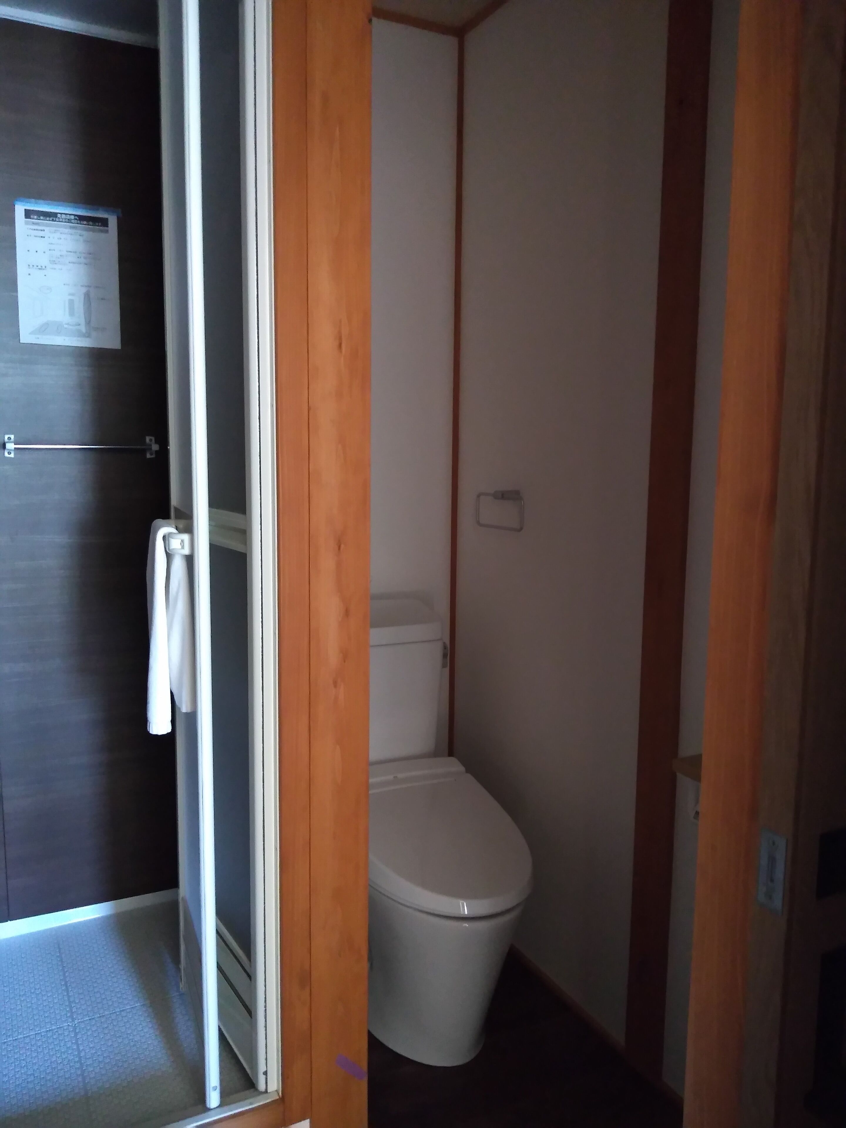 A small, narrow bathroom with a white toilet and a wooden door frame.