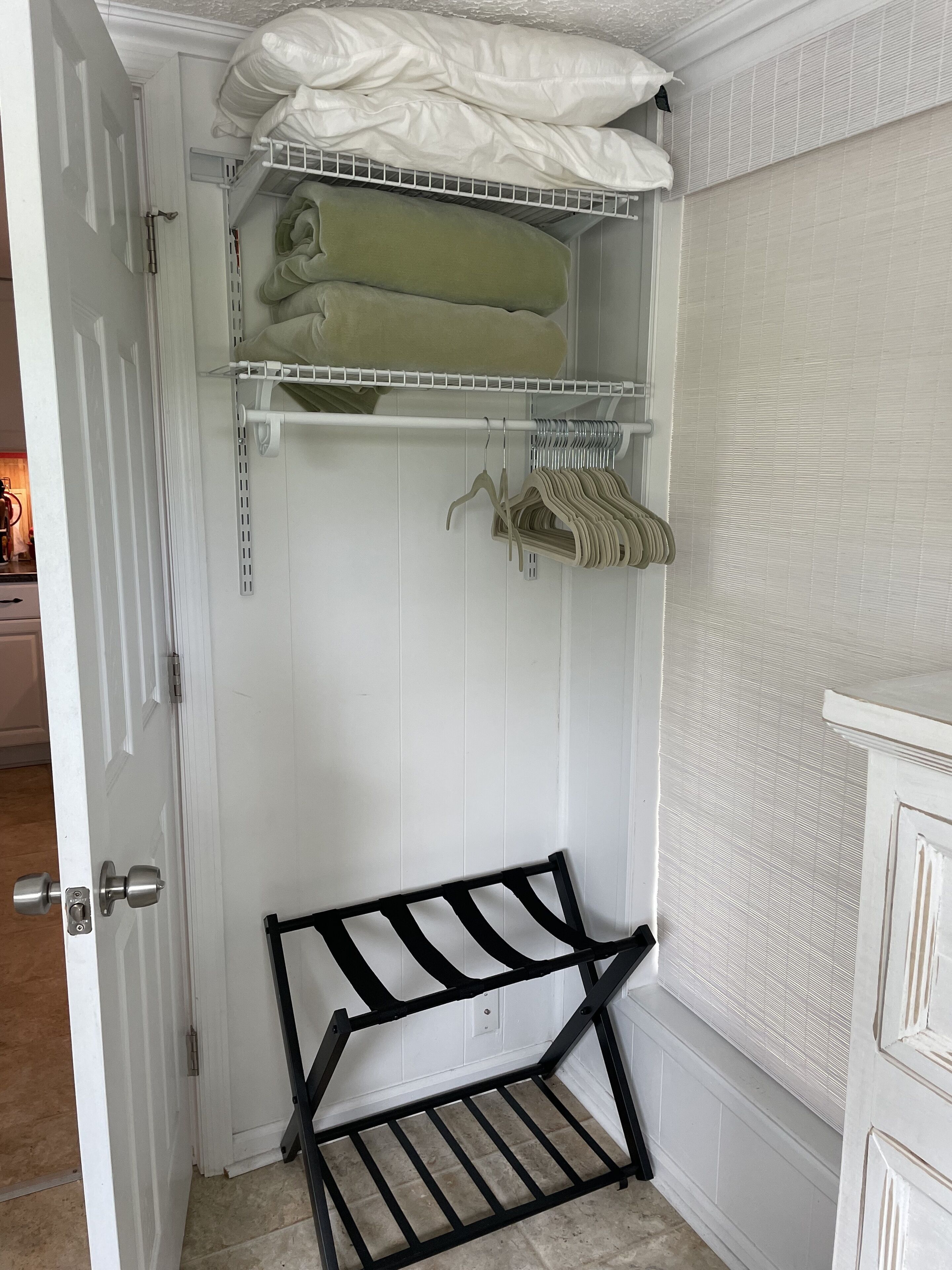 Ein weißer Schrank mit Regalen und einer Bank.