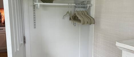 Ein weißer Schrank mit Regalen und einer Bank.