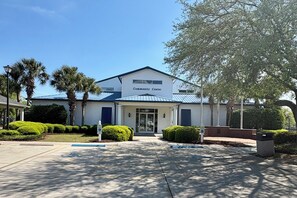 A community center with a white exterior, a blue roof, and a clear entrance. - Our Escape Near the Sea! Limo Golf Cart Included (Garden City)