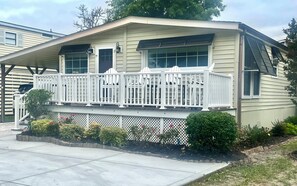 Ein Bungalow mit Veranda, einem kleinen Garten und einer Garage.
