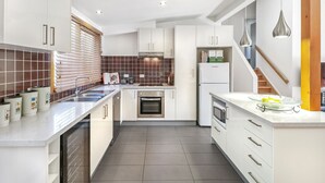 A modern kitchen with white cabinets, a built-in oven, a refrigerator, and a microwave. - Blackwood Chalet - Base of Buller (Sawmill Settlement)