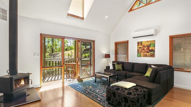 A spacious living room with a fireplace, a sofa, a coffee table, and a patterned rug. - Blackwood Chalet - Base of Buller (Sawmill Settlement)