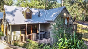 A wooden house with a porch, a chimney, and a small window. - Blackwood Chalet - Base of Buller (Sawmill Settlement)