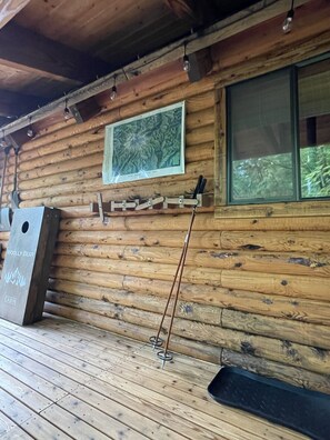 A wooden cabin interior with a mounted picture, a mounted knife rack, and a mounted fishing rod. - Woolly Bear Log Cabin Mountain Get-Away (Packwood)