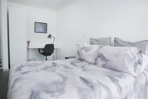 A modern bedroom with a large bed, a desk, and a chair.