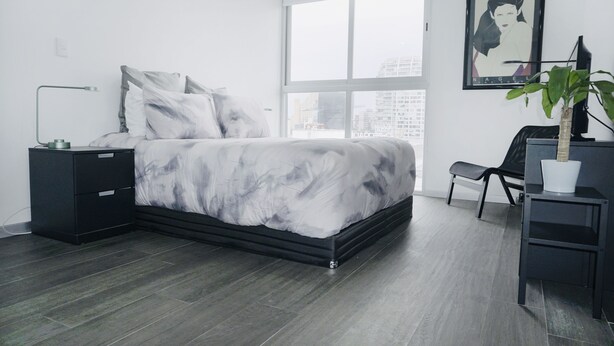 Ein modernes Schlafzimmer mit einem großen Bett, einem Nachttisch, einem Schreibtisch und einem Sessel.