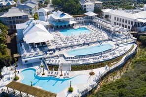 Un complexe hôtelier doté de plusieurs piscines, de chaises longues et d’un espace abrité.