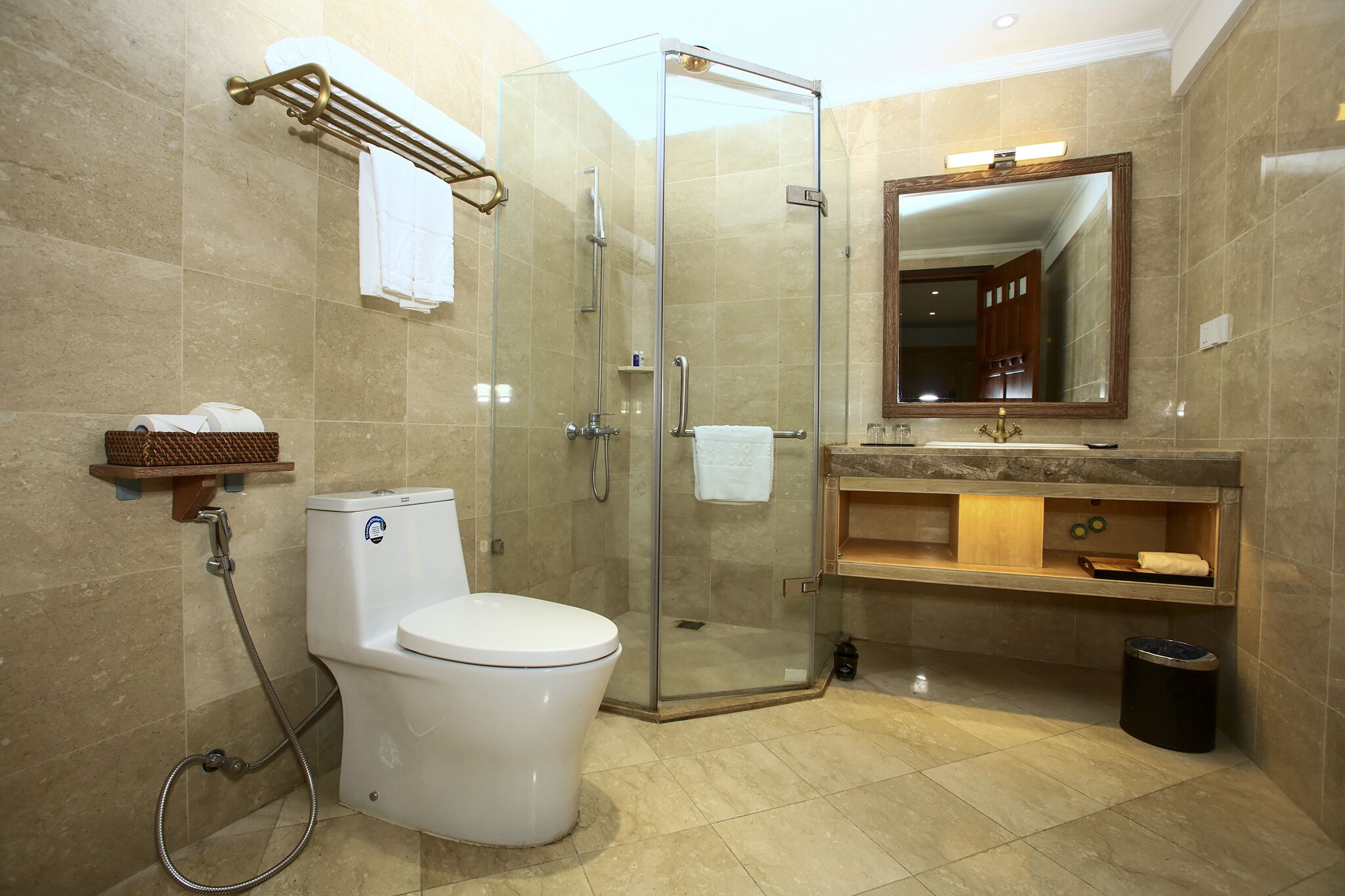 A modern bathroom with a glass-enclosed shower, a white toilet, a vanity with a mirror, and a trash can.