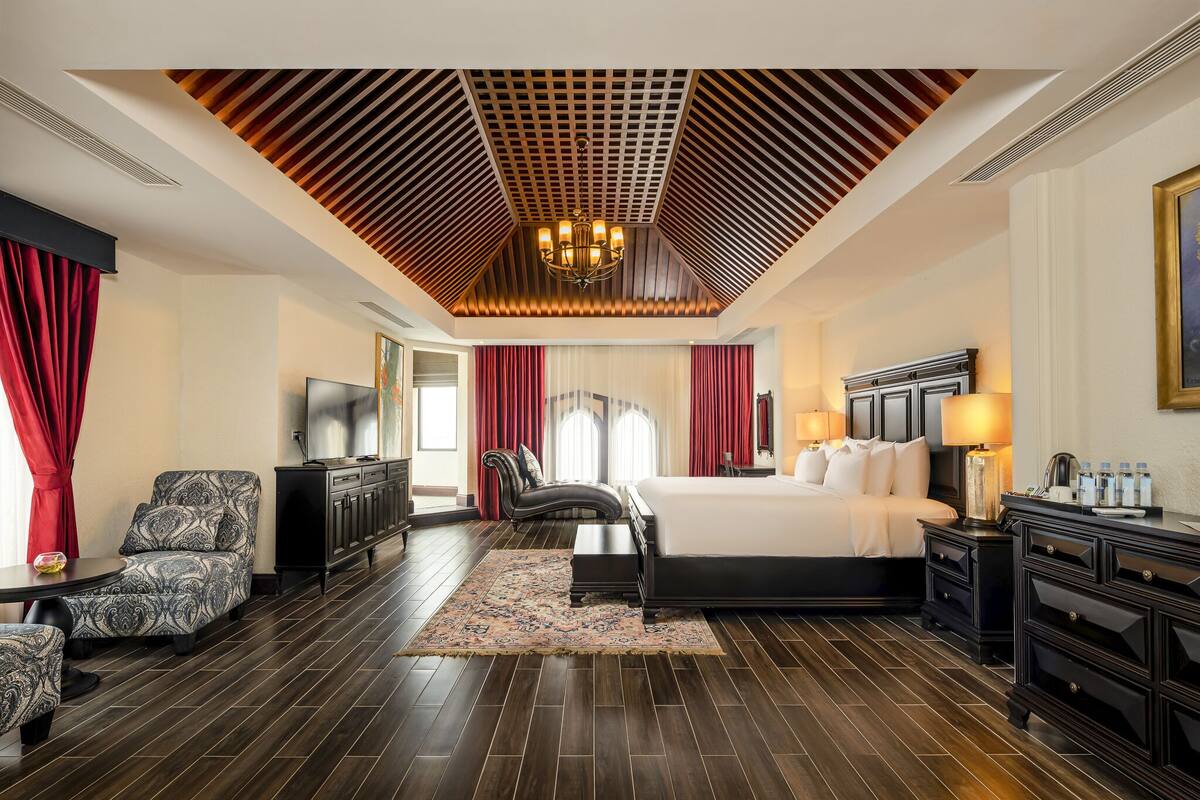 Une chambre d’hôtel avec un grand lit, une télévision, un bureau et une chaise.
