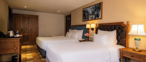 Habitación de hotel con dos camas, un escritorio y un cuadro en la pared.