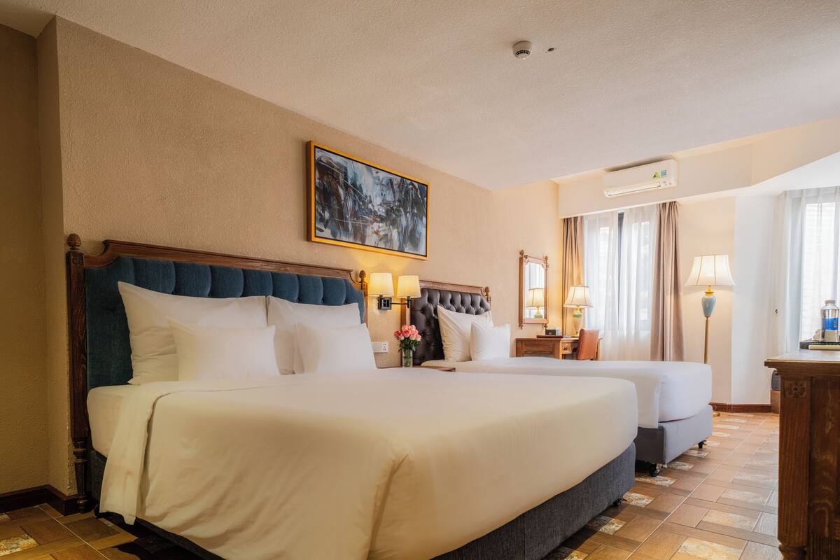 Une chambre d’hôtel avec deux lits, un grand tableau au mur et un appareil de climatisation.