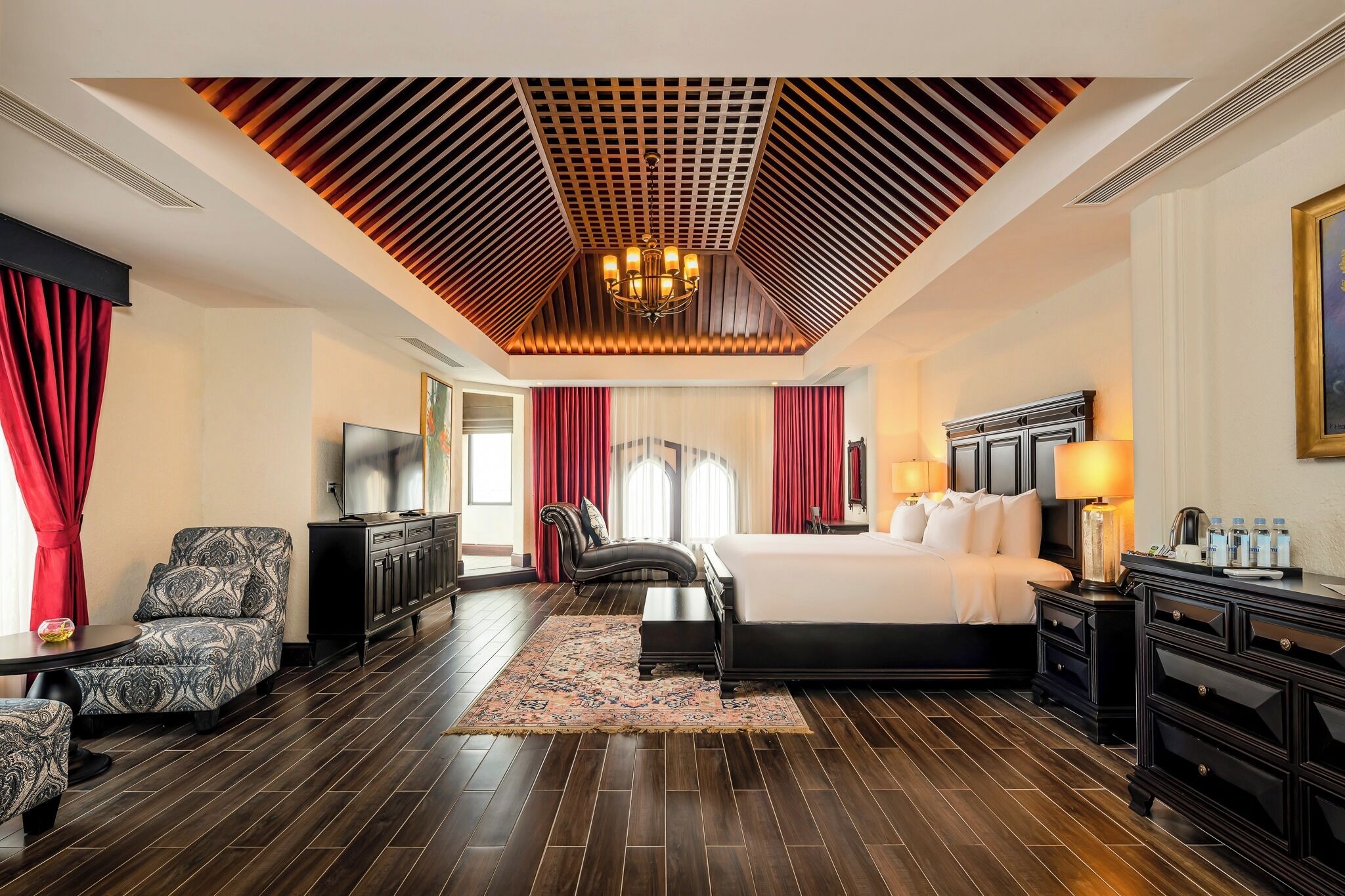 Een hotelkamer met een groot bed, een televisie, een bureau en een stoel.