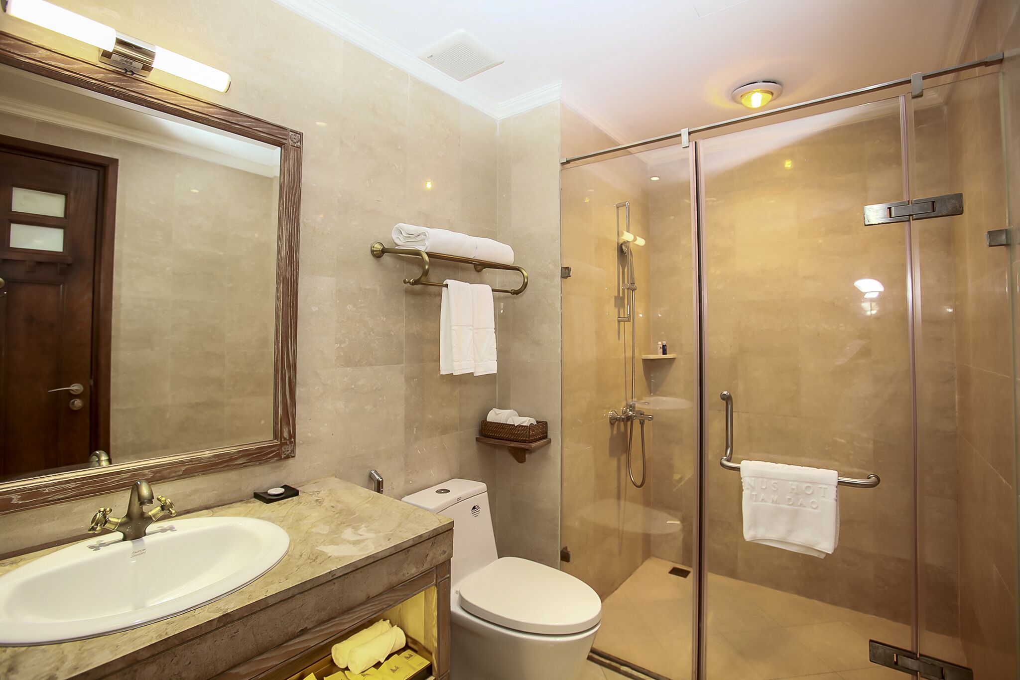 Une salle de bain équipée d’un lavabo, de toilettes et d’une douche à parois de verre.