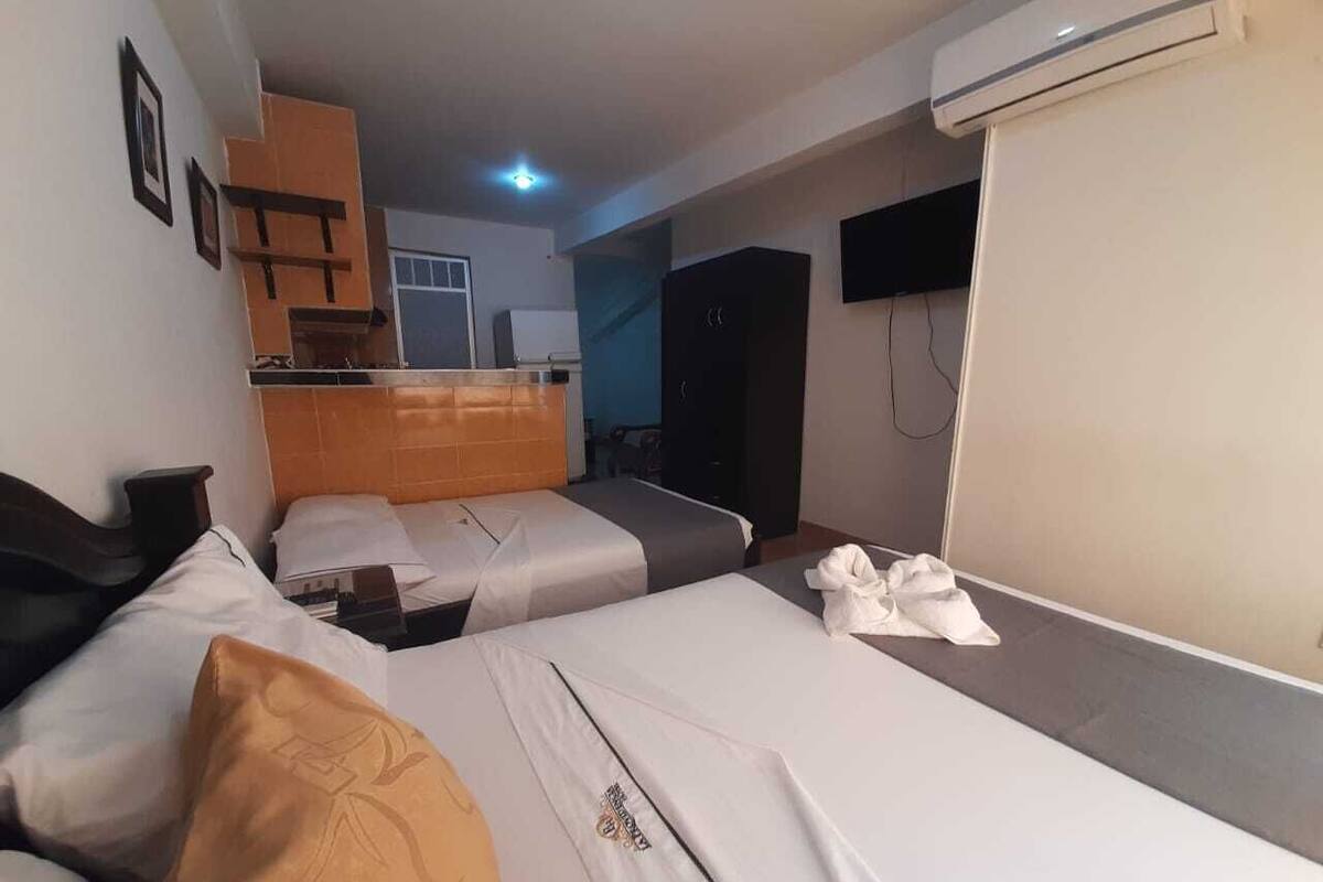Une chambre d’hôtel avec deux lits, une armoire, un petit coin cuisine et un appareil de climatisation.