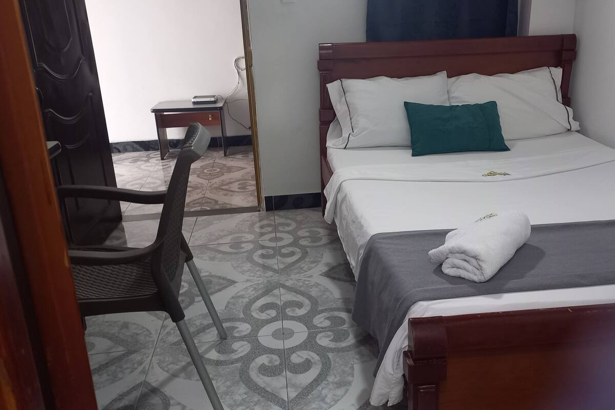 Une chambre d’hôtel avec un lit, une chaise, un bureau et un sol à motifs.