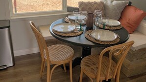Comedor con una mesa redonda dispuesta para cuatro personas, con individuales y platos tejidos.