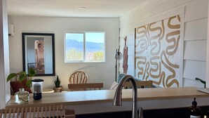 Una cocina moderna con un amplio ventanal, un fregadero y una zona de comedor con una silla y mesa.