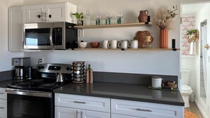 Una cocina moderna con electrodomésticos de acero inoxidable, armarios blancos y objetos decorativos en las estanterías.
