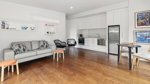 Un salon moderne avec un canapé gris, des fauteuils noirs et une table basse en bois.