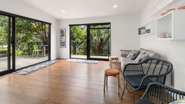Un vaste espace de vie doté de grandes portes-fenêtres coulissantes donnant sur un balcon, d’un canapé, de deux fauteuils et d’une table basse.