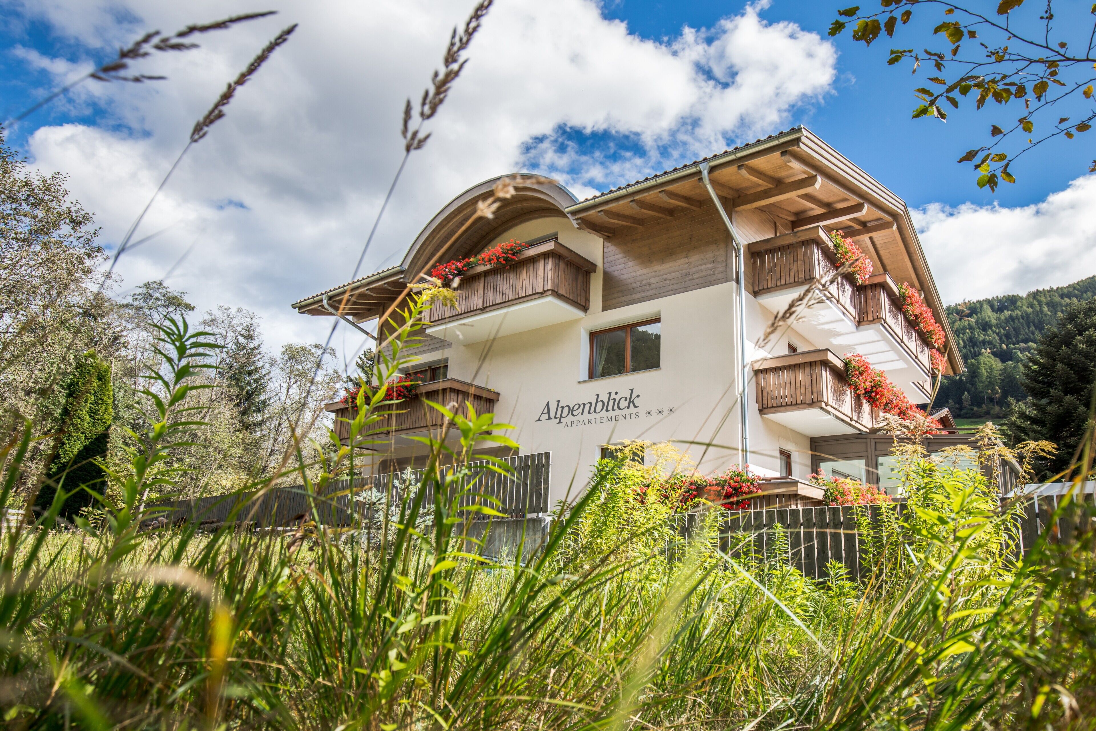 Un immeuble à plusieurs étages, doté de balcons, entouré de verdure et surplombant un ciel dégagé.