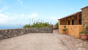 A building with a stone wall, a patio area, and potted plants. - Casa Chinamada with Sea View, Mountain View, Terrace & Wi-Fi (La Laguna)