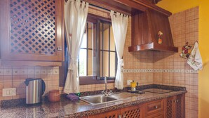 A kitchen with a stainless steel sink, wooden cabinets, a window with curtains, and a tiled backsplash. - Casa Chinamada with Sea View, Mountain View, Terrace & Wi-Fi (La Laguna)