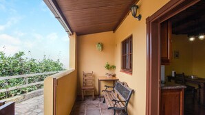 A covered outdoor area with a wooden bench, a table with chairs, and a small potted plant. - Casa Chinamada with Sea View, Mountain View, Terrace & Wi-Fi (La Laguna)