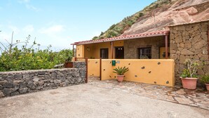 A stone building with a yellow facade, a covered porch, and potted plants. - Casa Chinamada with Sea View, Mountain View, Terrace & Wi-Fi (La Laguna)