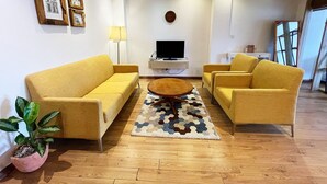 Un salon comprenant un canapé, des fauteuils, une table basse et un téléviseur.