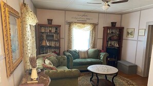 Un salon chaleureux avec un canapé vert, une table basse ronde et une bibliothèque.