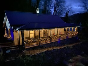 Un edificio con un porche decorado con luces y coronas, una zona cubierta con techo y un sendero vallado.