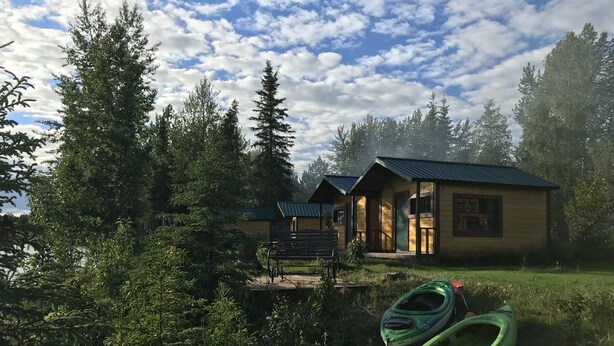 A cabin with a porch and a kayak nearby.