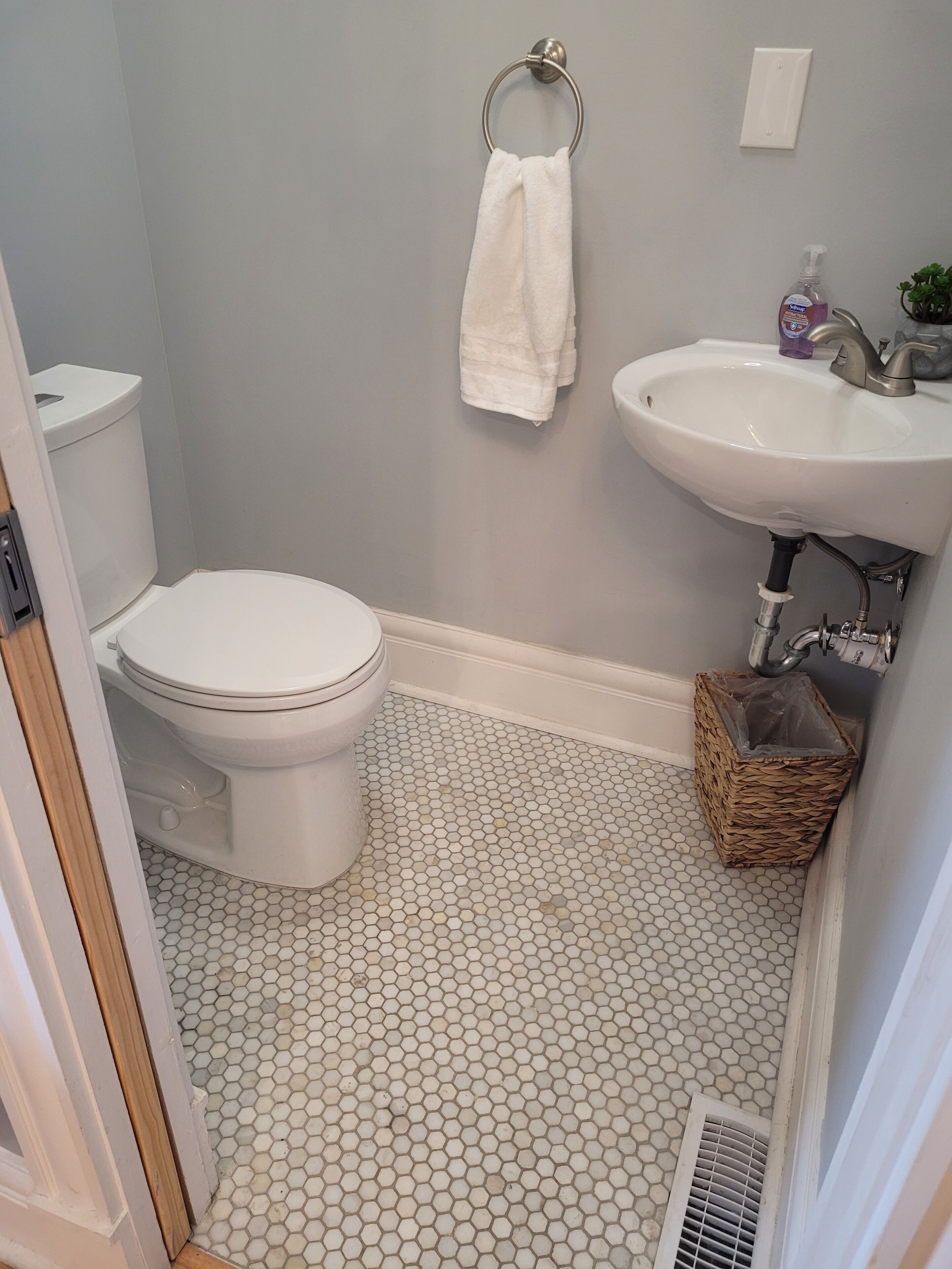 A bathroom with a toilet, sink, and a white towel hanging on the wall.