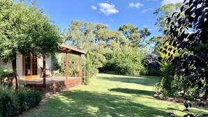 A wooden deck with a pergola, a lawn, and a house with a glass door.