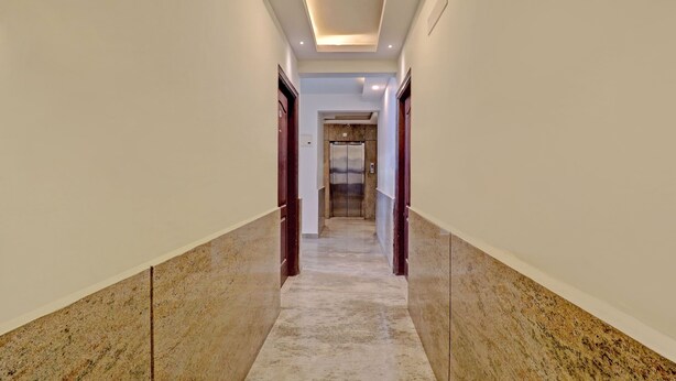 A corridor with marble flooring, wooden doors, and a ceiling with recessed lighting.