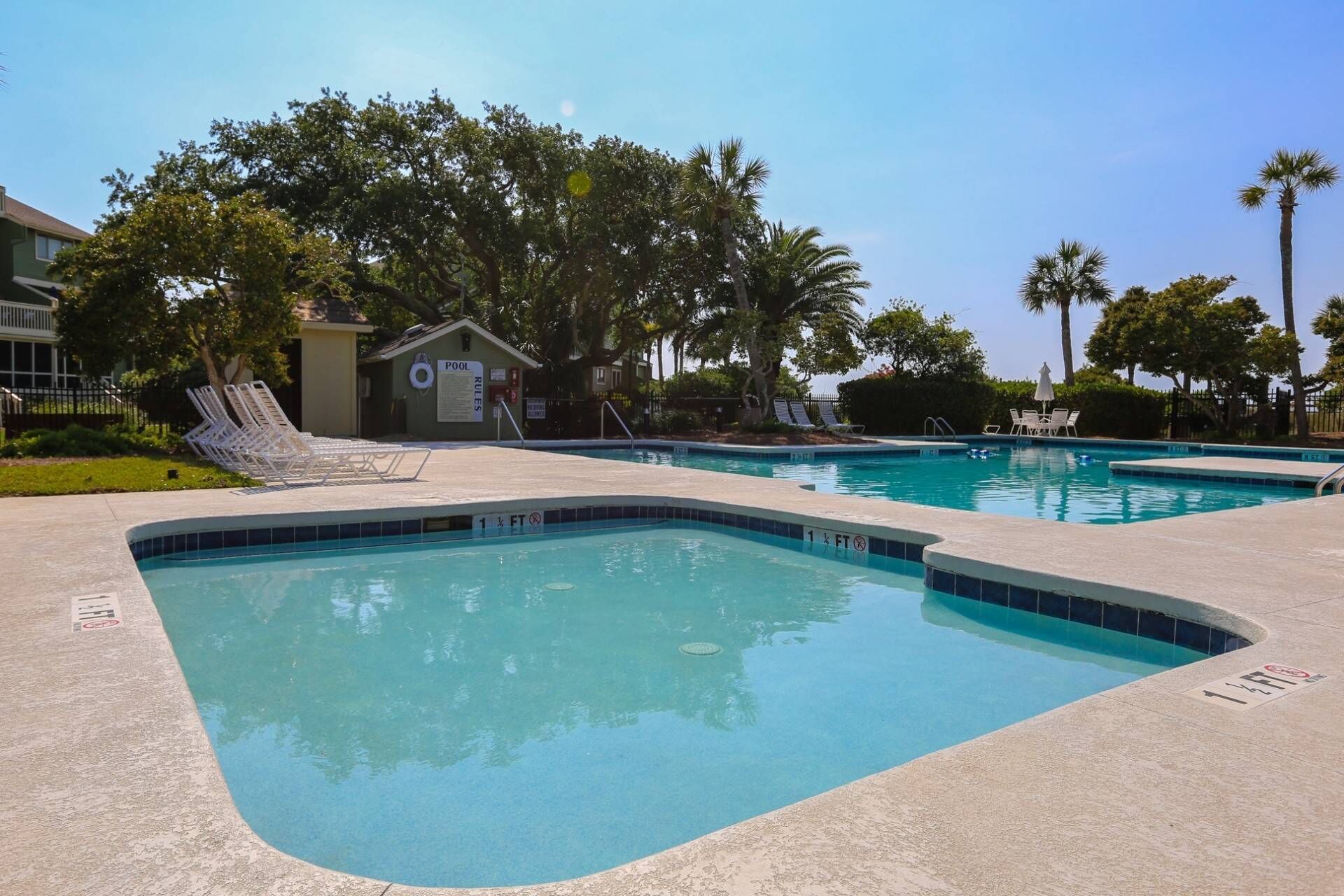 A pool area with clear blue water, lounge chairs, and a lifeguard tower.