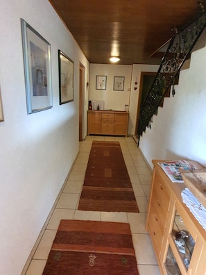 Un couloir avec deux tapis marron, des meubles en bois et des tableaux encadrés accrochés aux murs.