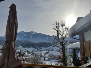Un paysage de montagne enneigé, avec un ciel dégagé et un soleil brillant.