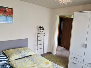 A bedroom with a bed, a wardrobe, a radiator, and a painting on the wall.