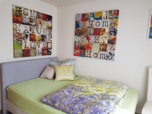 A bedroom with a bed, pillows, and two wall art pieces.