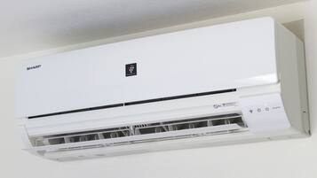 Un equipo de aire acondicionado blanco con panel de control y compartimento para el filtro.
