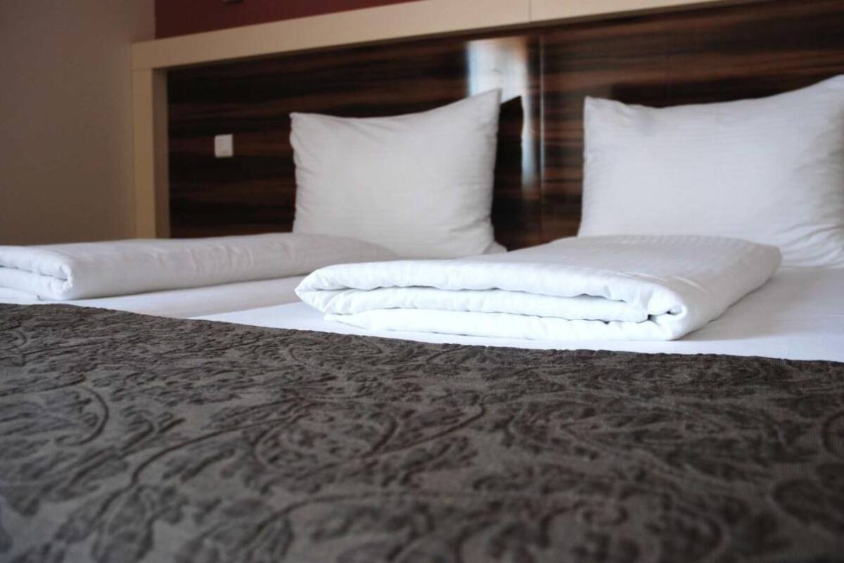 A neatly made bed with white linens and a patterned bedspread.
