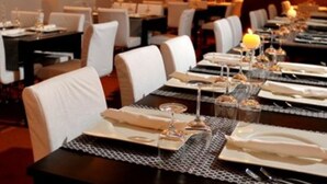 A restaurant with tables set for dining, featuring a warm ambiance with wall-mounted lights and a framed artwork on the wall. - Hotel Terra (Novalja)