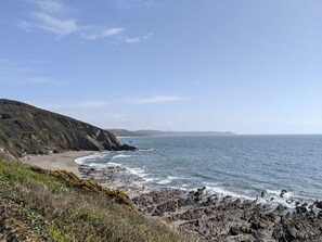 Un paisaje costero con una costa rocosa, una playa arenosa y cielo despejado.