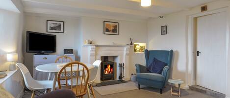 A living room with a fireplace, a television, and a blue armchair.